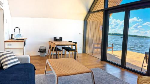 a living room with a table and a view of the water at Domy na Wodzie na Mazurach in Pisz