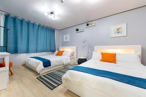 2 camas en una habitación con cortinas azules en Luda house en Seúl