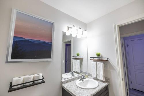 uma casa de banho branca com um lavatório e um espelho em 8 BEDS Tomorrowland - 15 Minutes To The Falls em Thorold