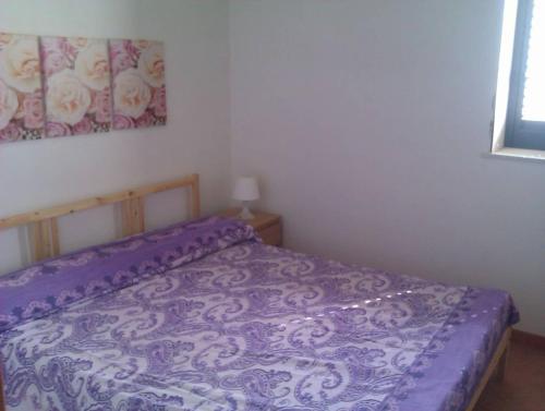 a bed with a purple comforter in a bedroom at 1st floor apartment in villa Falari near the in Avola