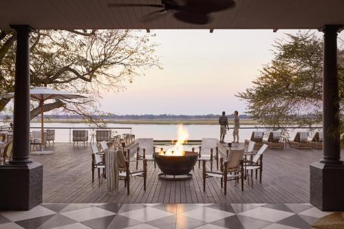 a fire pit on a deck with tables and chairs at Zambezi Grande Private Game Experience in Mafuta