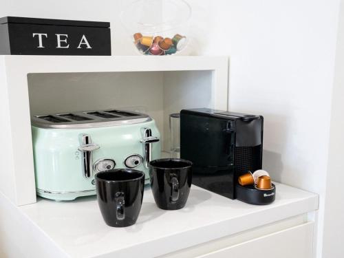 a shelf with two coffee cups and a coffee maker at Riptide on Surf Beach in Kiama