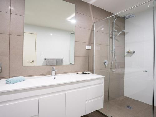 a bathroom with a white sink and a shower at Riptide on Surf Beach in Kiama