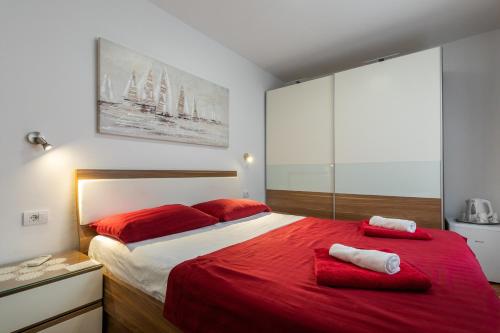a bedroom with a large red bed with red pillows at Rooms Edna in Dubrovnik