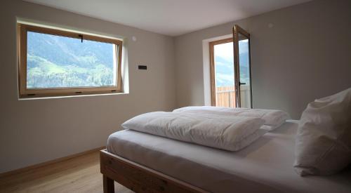 a white bedroom with a bed and a window at Bergchalet Prantach in San Martino