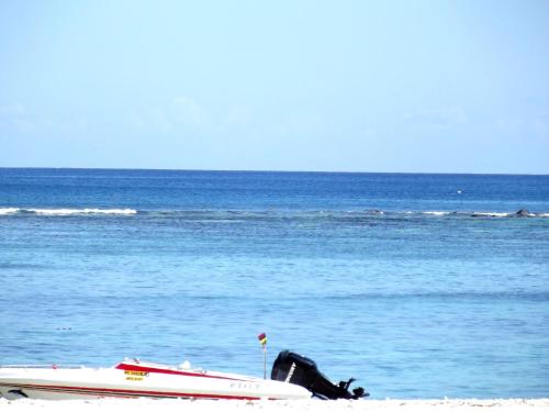 a boat sitting on the beach next to the ocean at West Sand Holidays LICENSED BY THE TOURISM AUTHORITY 09926 in Flic-en-Flac