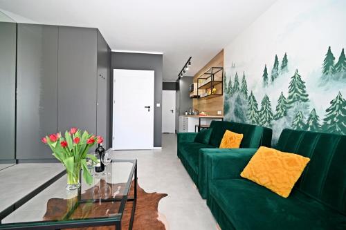 un soggiorno con un divano verde e un tavolo di Szczyrk Apartament Natura z Sauną nad Żylicą a Szczyrk