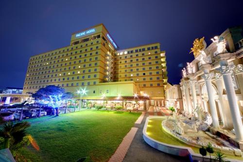 a hotel with a large lawn in front of a building at Pacific Hotel Okinawa in Naha