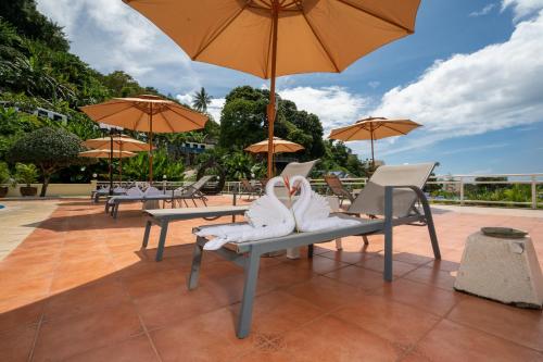 a pair of white shoes sitting on a bench with an umbrella at Memory Karon Resort in Karon Beach