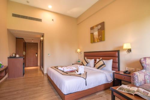 a hotel room with a bed and a chair at The Lalita Grand Mathura- Vrindavan in Mathura