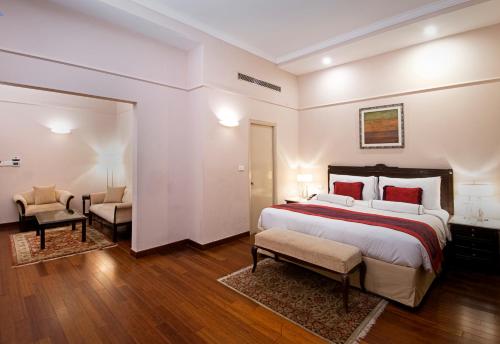 a bedroom with a large bed and two chairs at The Claridges New Delhi in New Delhi
