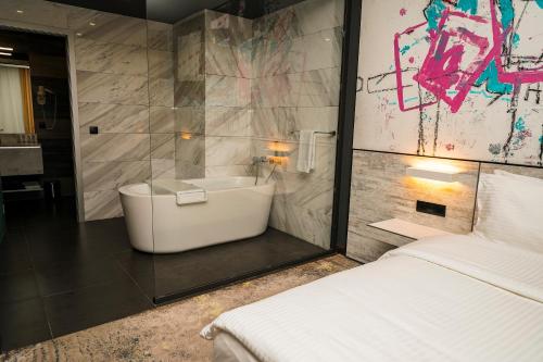 ein Bad mit einer Badewanne, einem Waschbecken und einem Bett in der Unterkunft Messier 53 Hotel Yerevan in Yerevan