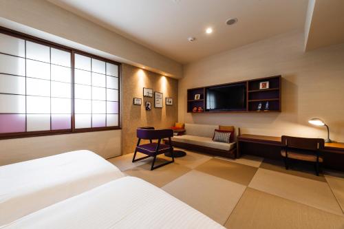 a bedroom with a bed and a couch and a tv at PROSTYLE RYOKAN Naha Kenchou Mae in Naha