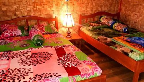 a bedroom with two beds and a table with a lamp at Ijen Miner Family Homestay in Banyuwangi