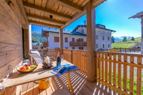 eine Holzterrasse mit einem Tisch auf dem Balkon in der Unterkunft Lina, Giulia, Lucia - Happy Rentals in Livigno