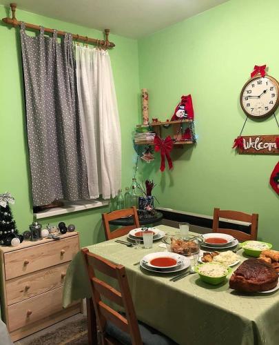 a dining room with a table with food and a clock at Vila Vedrana Apartman Nedeljkovic in Brzeće