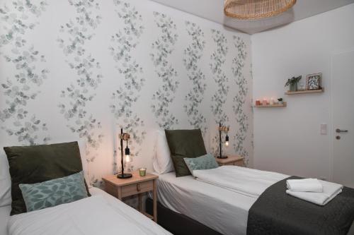 two beds in a room with floral wallpaper at Great apartment with view and heated rooftop Pool in Vienna