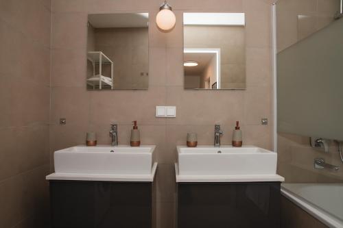 two white sinks in a bathroom with a mirror at Great apartment with view and heated rooftop Pool in Vienna