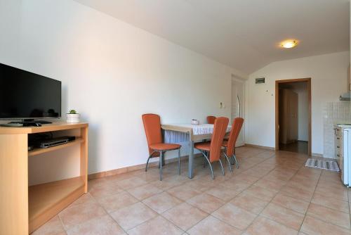 a dining room with a table and chairs and a television at Apartments Branimir in Murter
