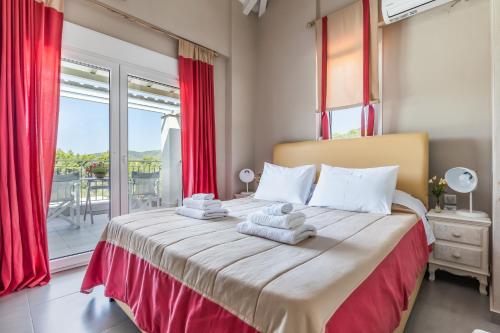 a bedroom with a large bed with red curtains at Villa Aelia by Kardous in Alikias