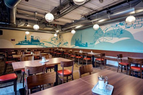 a restaurant with wooden tables and chairs and a mural at THE 4YOU Hostel & Hotel Munich in Munich