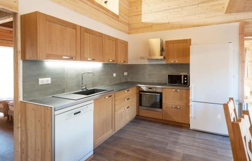 a kitchen with wooden cabinets and a white refrigerator at Odalys Chalet D'Alice in Les Menuires