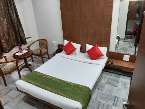 a bedroom with a bed with red pillows and a table at City Palace Hotel होटल सिटी पैलेस in Nashik