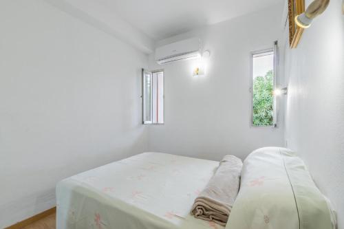 ein weißes Zimmer mit einem Bett mit einem Fenster in der Unterkunft Retirosol Bungalow in Denia