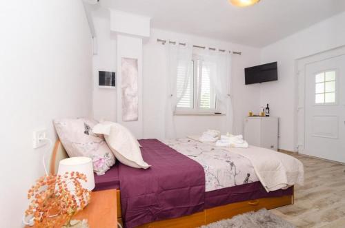Dormitorio blanco con cama con sábanas moradas en Apartment & Room Lady O, en Dubrovnik