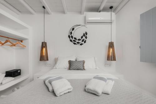 a white bedroom with a bed with two pillows at Xerolithos Natural Living in Naxos Chora