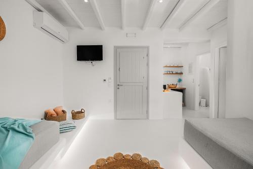 a white living room with a couch and a tv at Xerolithos Natural Living in Naxos Chora