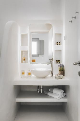 a white bathroom with a sink and a mirror at Xerolithos Natural Living in Naxos Chora