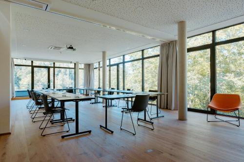 a conference room with tables and chairs and windows at Das Graseck - mountain hideaway & health care in Garmisch-Partenkirchen