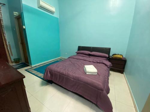 a bedroom with a purple bed with a towel on it at illiy's homestay in Tangga Batu