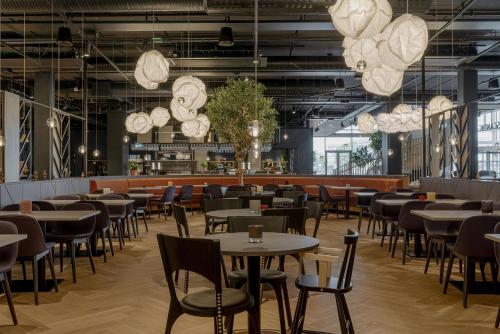 a restaurant with tables and chairs and chandeliers at Scandic Landvetter in Landvetter