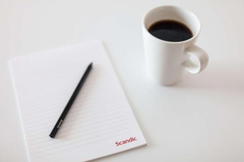 a pen and a cup of coffee on a notebook at Scandic Gällivare in Gällivare