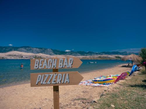 a sign on a beach with a beach bar pizza at Terra Park SpiritoS in Kolan