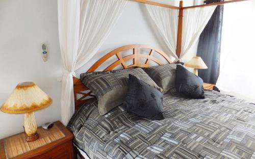 1 dormitorio con 1 cama con almohadas y lámpara en Superb Split Level Waterside Apt, Marigot Bay, St Lucia WI, en Castries