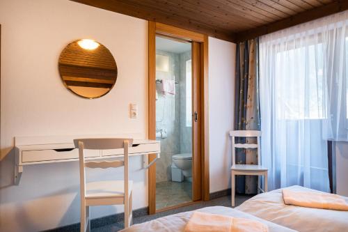 a bedroom with a desk and a bed and a bathroom at Naturpension Mühlhof in Neukirchen am Großvenediger