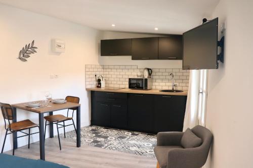 una cocina con armarios negros, mesa y sillas en Moulin 1- Appartement Arènes Romaines - Beziers centre - Wifi - Tv connectée en Béziers