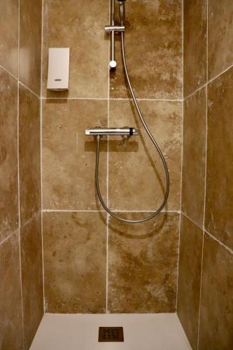 une douche avec un tuyau sur un mur carrelé dans l'établissement Moulin 1- Appartement Arènes Romaines - Beziers centre - Wifi - Tv connectée, à Béziers