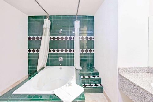 y baño de azulejos verdes con bañera. en Travelodge by Wyndham Banning Casino and Outlet Mall, en Banning