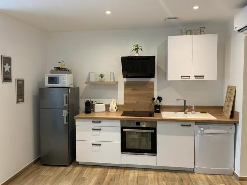 a kitchen with white cabinets and a sink and a refrigerator at cekalauthymae in Borgo