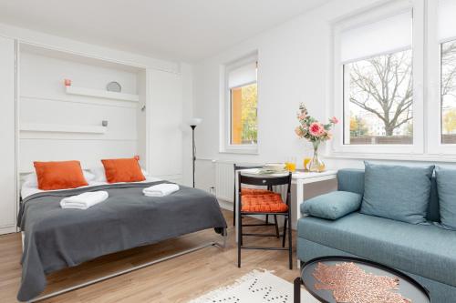 a bedroom with a bed and a blue couch at Studio Apartment Ochota Siemieńskiego by Renters in Warsaw