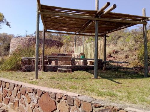 a pavilion with a stone wall in a field at Bateleur Nature Reserve in Modimolle