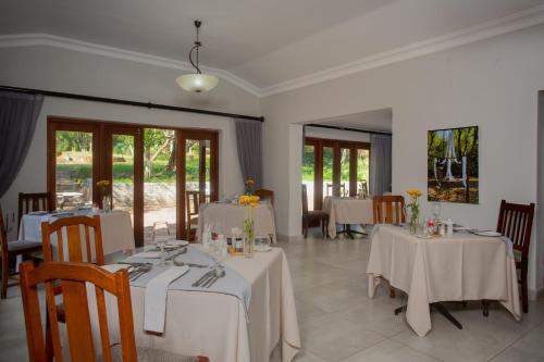 a dining room with two tables with white tablecloths at Whispering Pines Country Estate in Magaliesburg