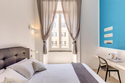 a bedroom with a bed and a desk and a window at Manin Suites LT in Rome