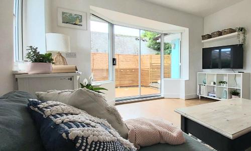 a living room with a couch and a tv at Kindly Light Beach House, Borth-y-Gest in Porthmadog