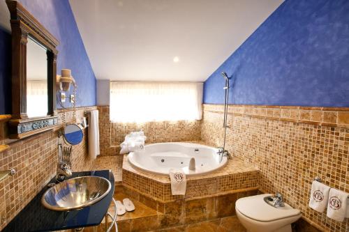 a bathroom with a tub and a toilet and a sink at Abba Palacio de Soñanes Hotel in Villacarriedo