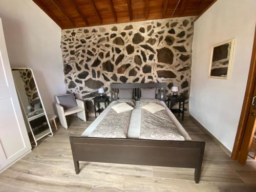 a bedroom with two beds and a stone wall at Casa Sol in Hermigua